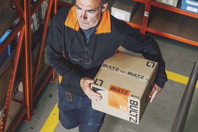 Operario de Bultz transportando una caja de pedido en el almacén