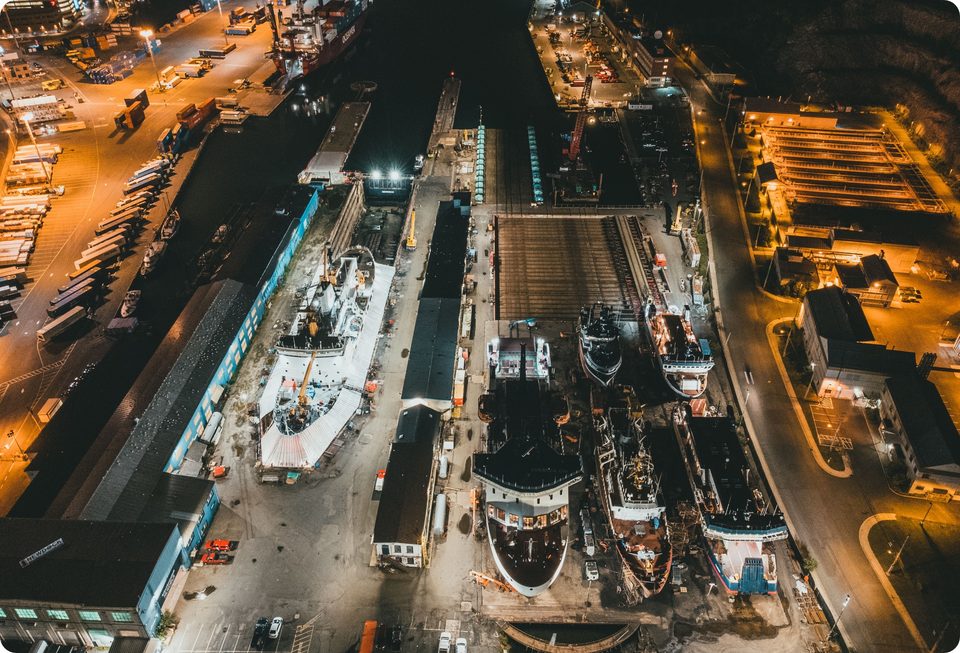 Vista aérea nocturna de un astillero con buques en dique seco